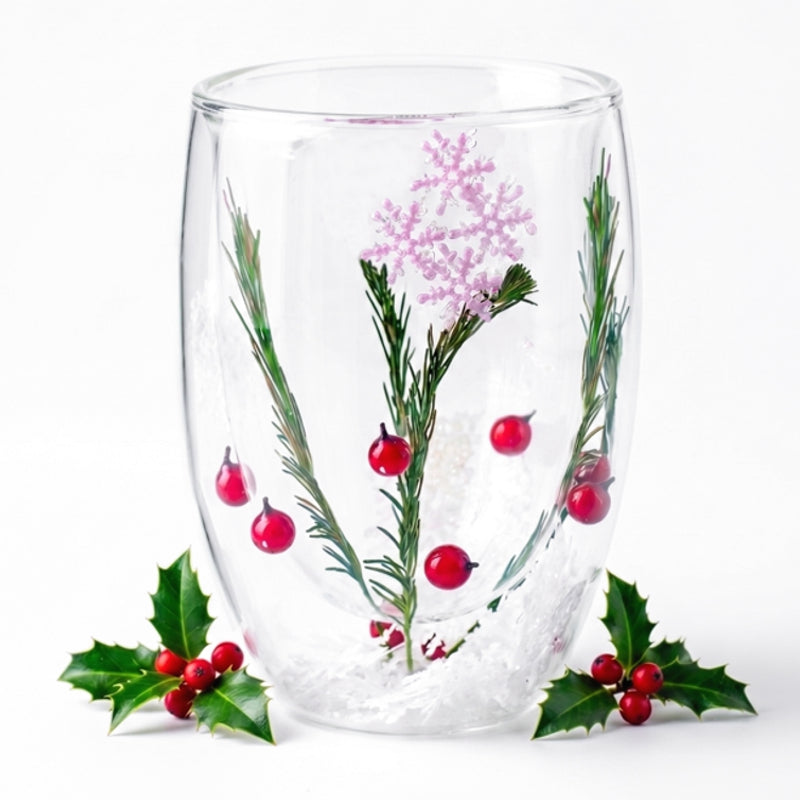 Verre à double paroi sur le thème de Noël contenant des aiguilles de pin, baies rouges, flocon scintillant et fausse neige, encadré de branches de houx