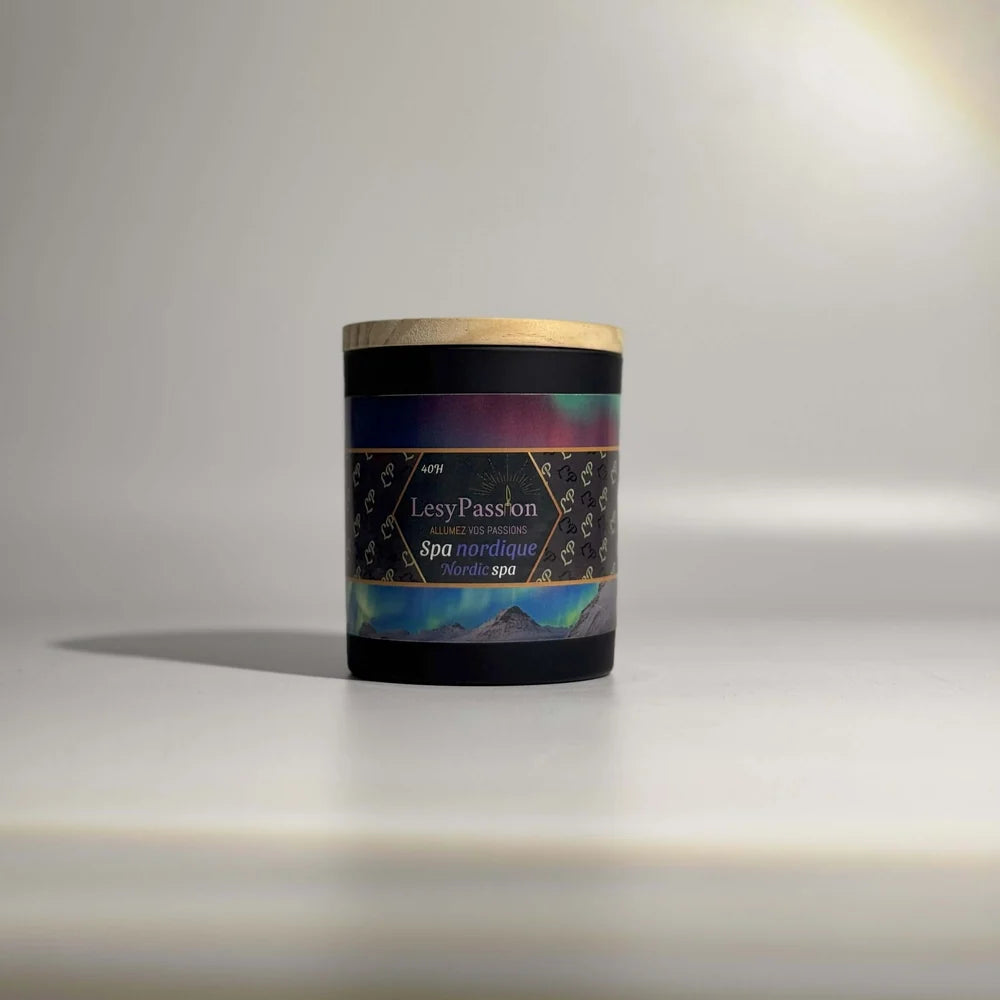 Bougie parfumée format 9 oz (40 h) en pot cylindrique noir mat avec couvercle en bois clair, dotée d'une étiquette « LesyPassion - Spa nordique / Nordic spa » illustrée d'aurores boréales au-dessus de montagnes enneigées, sur fond studio neutre.