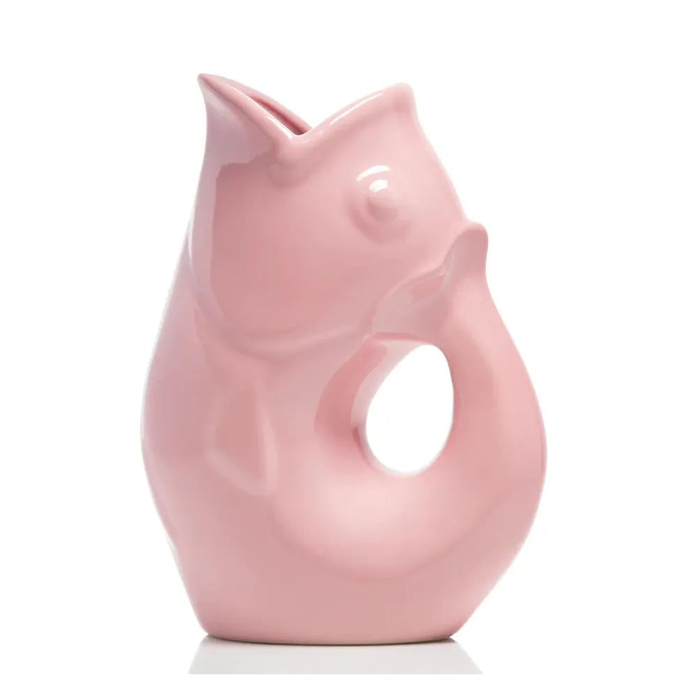 Carafe décorative (Gurgle Pot) en céramique émaillée de couleur rose, sculptée en forme de poisson dressé dont la gueule ouverte sert de bec verseur et le corps courbé forme l'anse.