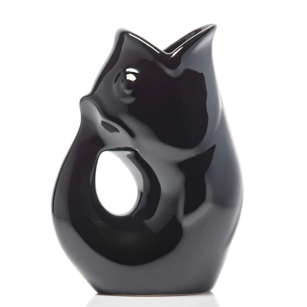 Carafe décorative (Gurgle Pot) en céramique émaillée noire brillante, sculptée en forme de poisson dressé dont la gueule ouverte sert de bec verseur et le corps courbé forme l'anse.