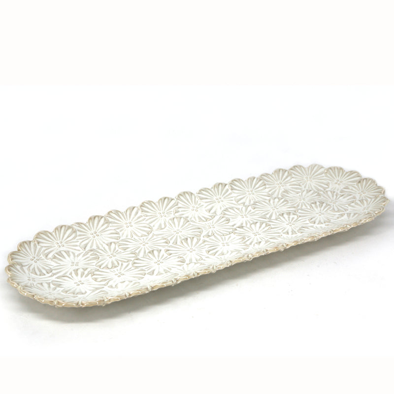 Plat de service allongé en céramique blanc cassé orné d'un motif floral texturé et d'un rebord festonné, le bouquet de Danesco