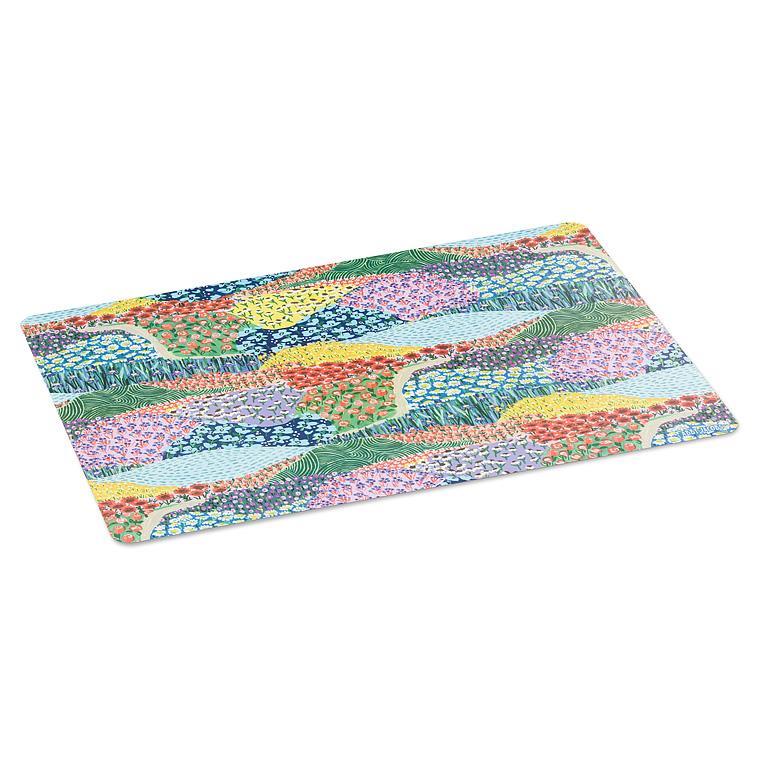 Napperon rectangulaire présenté en angle, illustré d'un paysage printanier coloré de collines fleuries traversées de petits sentiers.