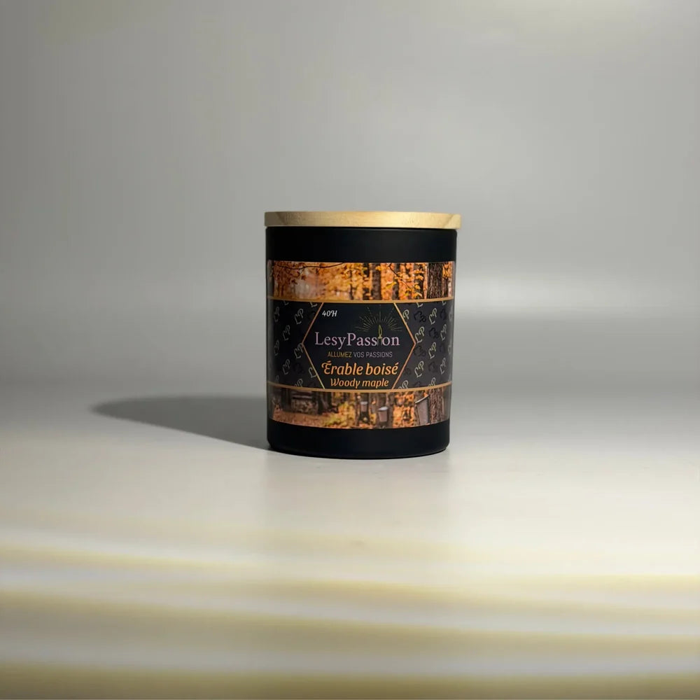 Bougie parfumée format moyen (40 h) en pot cylindrique noir mat avec couvercle en bois clair, arborant l'étiquette aux motifs d'érables d'automne « Érable boisé / Woody maple » de la marque LesyPassion sur fond studio épuré.