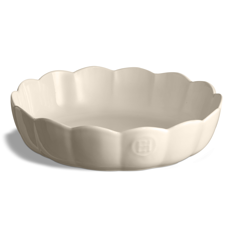 Plat ou coupelle de service circulaire en céramique brillante de couleur creme. Les rebords sont ondulés et évasés en forme de corolle de fleur. Le sceau de la marque Emile Henry (« EH ») apparaît en relief sur la paroi extérieure avant. L'objet est présenté vide et centré sur un fond blanc neutre.