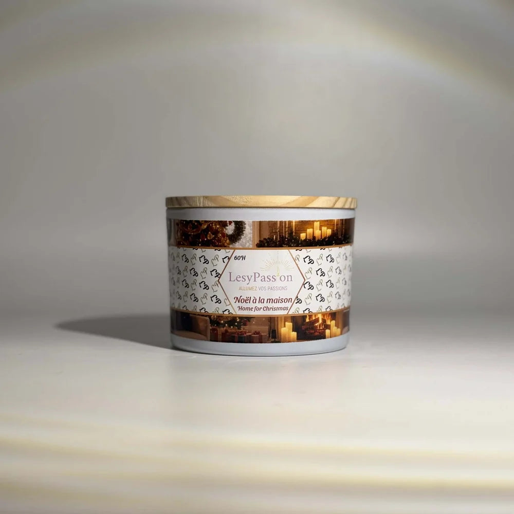 Bougie parfumée grand format (60 h) en pot blanc avec couvercle en bois clair, étiquette festive « LesyPassion - Noël à la maison / Home for Christmas » illustrée de bougies chaleureuses.