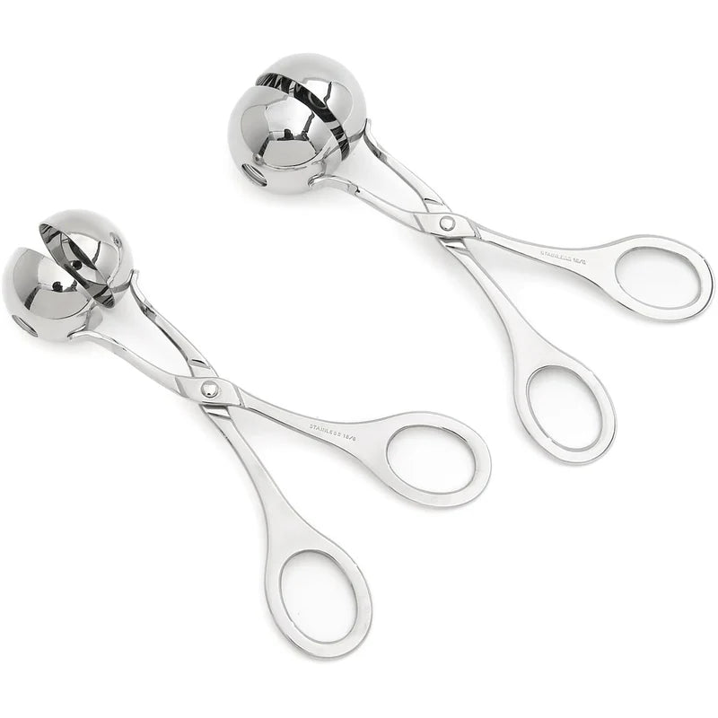 Deux pinces à boulettes en acier inoxydable argenté sur fond blanc. Chaque pince a la forme de ciseaux avec des anneaux pour les doigts à une extrémité et deux demi-sphères creuses à l'autre bout, qui s'assemblent pour former une boule complète lorsque la pince est fermée. L'une des pinces est légèrement ouverte, montrant l'intérieur des demi-sphères, tandis que l'autre est fermée. Sur le manche des deux pinces, l'inscription "STAINLESS 18/0" est visible.