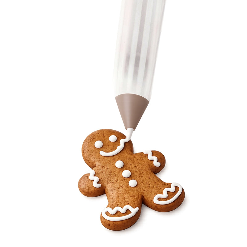 Mise en situation montrant un stylo de précision traçant des lignes de glaçage royal blanc sur un biscuit de Noël en forme de bonhomme en pain d'épices sur fond blanc